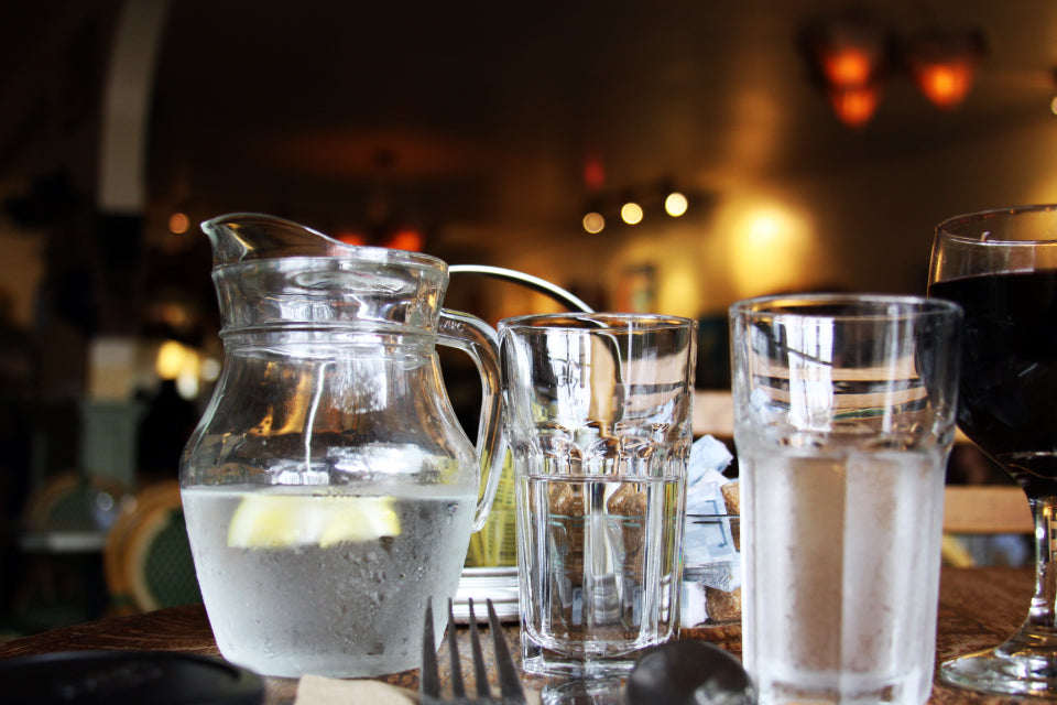 A pitcher and glasses of water on a counter